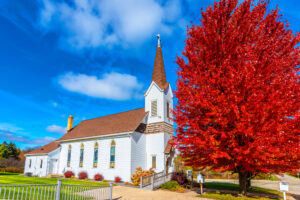 church with beautiful tree covered in red leaves out front